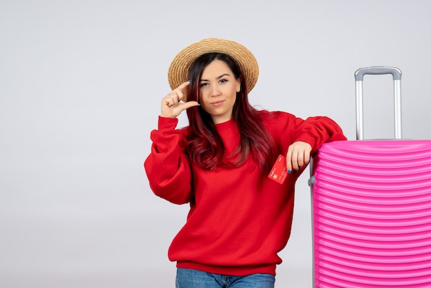 Vue de face jeune femme avec un sac rose tenant une carte bancaire sur un mur blanc