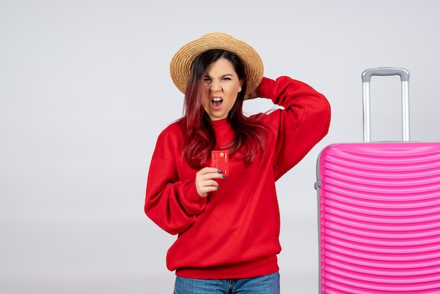 Vue de face jeune femme avec un sac rose tenant une carte bancaire sur un mur blanc