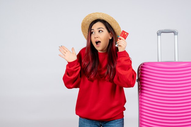 Vue de face jeune femme avec un sac rose tenant une carte bancaire sur un mur blanc