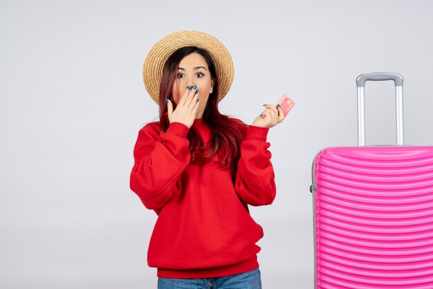 Vue de face jeune femme avec un sac rose tenant une carte bancaire sur un mur blanc