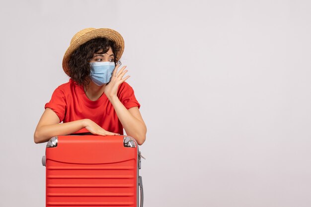 Vue de face jeune femme avec sac rouge en masque sur fond blanc couleur soleil covid- virus touristique de vacances pandémique