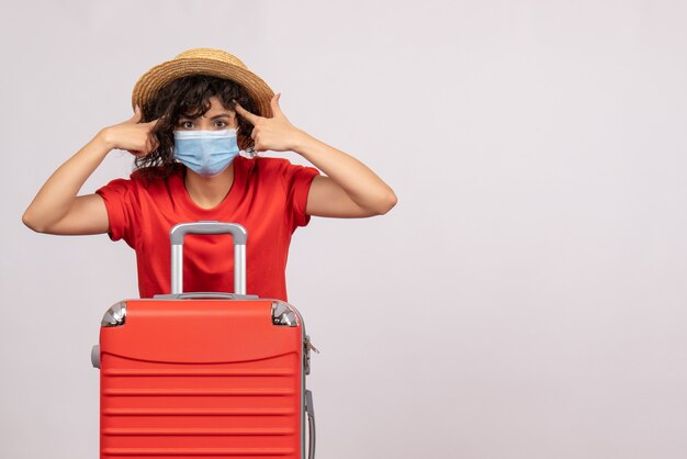 Vue de face jeune femme avec sac rouge en masque sur fond blanc soleil covid pandémie vacances voyage touriste virus couleur