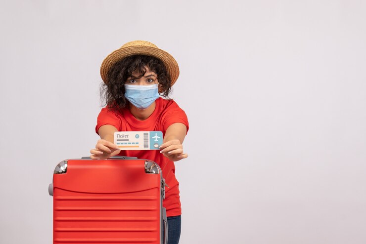 Photo gratuit vue de face jeune femme avec sac rouge en masque tenant un billet sur fond blanc soleil covid pandémie voyage de vacances couleur touristique