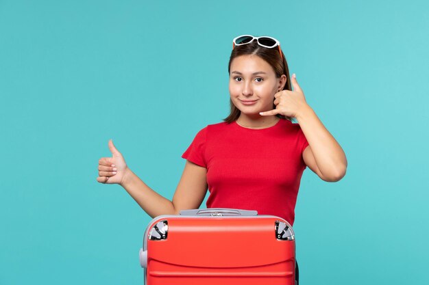 Vue de face jeune femme avec sac rouge préparation pour des vacances sur fond bleu mer voyage vacances voyage voyage