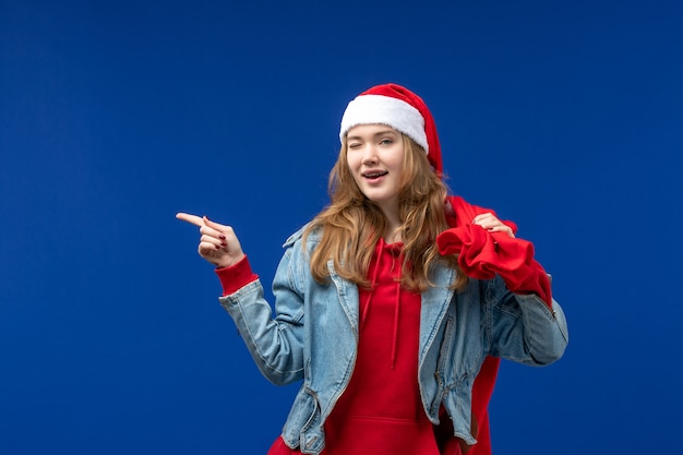 Vue de face jeune femme sac de transport plein de cadeaux sur les émotions de couleur de plancher bleu Noël