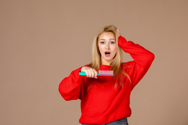 Photo gratuite vue de face jeune femme se brosser les cheveux sur un mur marron