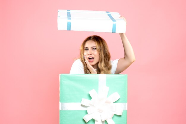 Vue de face jeune femme se cachant à l'intérieur de la boîte présente