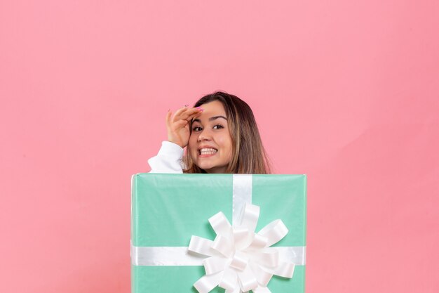 Vue de face jeune femme se cachant à l'intérieur présent sur le fond rose