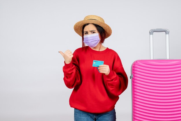 Vue de face jeune femme se préparant au voyage en masque sur mur blanc