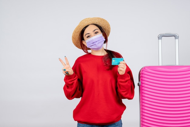 Vue de face jeune femme se préparant au voyage en masque sur mur blanc