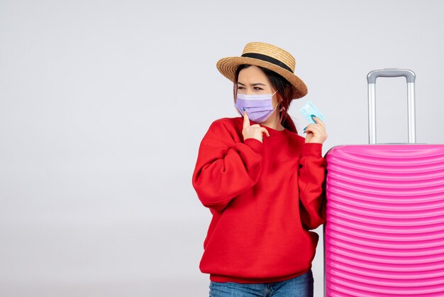 Vue de face jeune femme se préparant au voyage en masque sur mur blanc