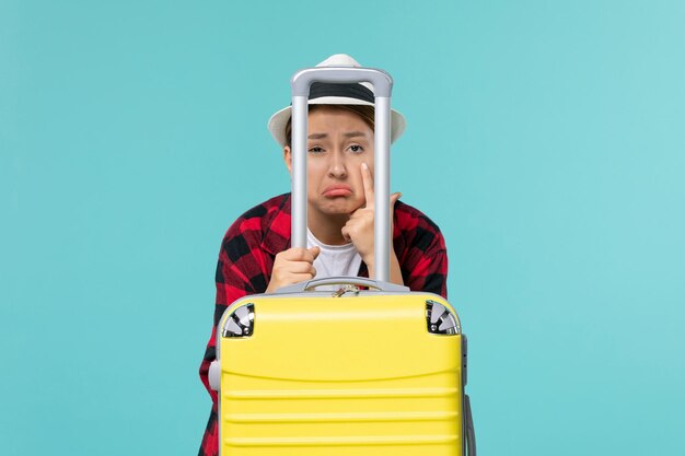 Vue de face jeune femme se préparant pour le voyage avec son sac jaune sur l'espace bleu