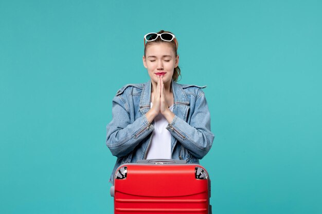 Vue de face jeune femme se prépare pour le voyage en priant sur l'espace bleu