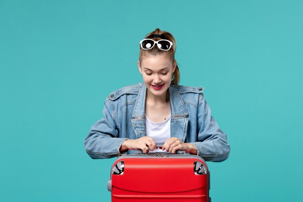 Vue de face jeune femme se prépare pour le voyage et se sentir excité sur l'espace bleu clair