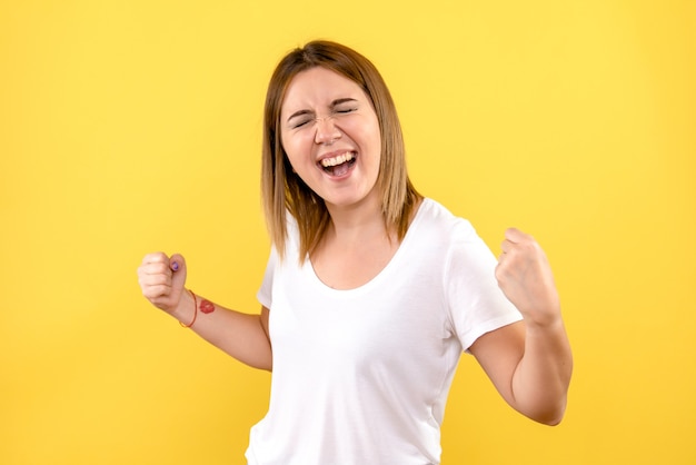 Vue de face de la jeune femme se réjouissant sur le mur jaune