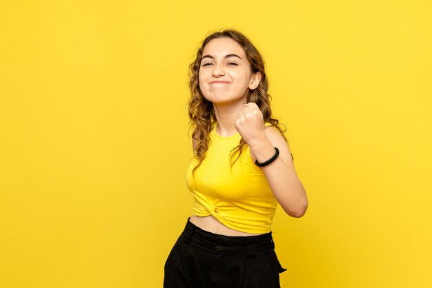 Vue de face de la jeune femme se réjouissant sur le mur jaune