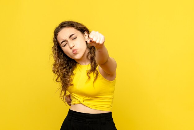 Vue de face de la jeune femme se réjouissant sur le mur jaune