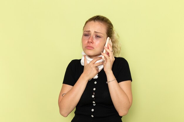 Vue de face jeune femme se sentant très malade et malade de parler au téléphone sur le mur vert maladie médecine féminine maladie