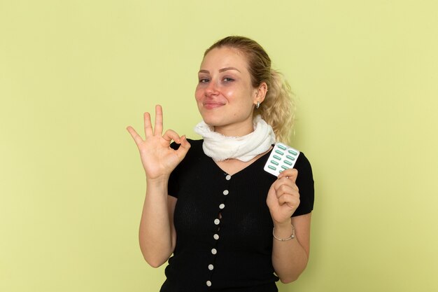 Vue de face jeune femme se sentant très malade et malade tenant des pilules sur le mur vert maladie médecine maladie