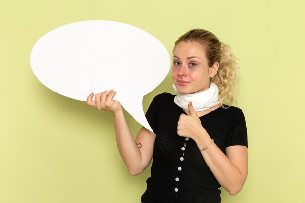 Photo gratuite vue de face jeune femme se sentir très malade et malade tenant un énorme panneau blanc sur le bureau vert maladie médecine maladie santé