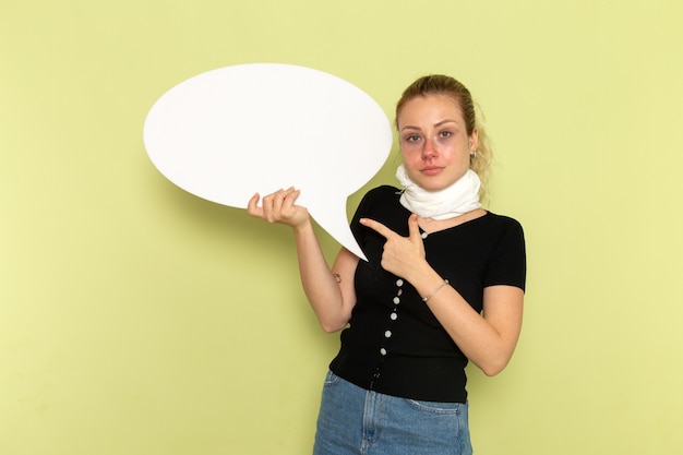 Photo gratuite vue de face jeune femme se sentir très malade et malade tenant un énorme panneau blanc posant sur un mur vert clair maladie médecine maladie santé