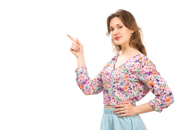 Une vue de face jeune femme séduisante en chemise à fleurs colorées et jupe bleue sur le blanc