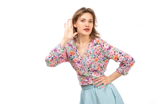 Une vue de face jeune femme séduisante en chemise à fleurs colorées et jupe bleue posant sur le blanc