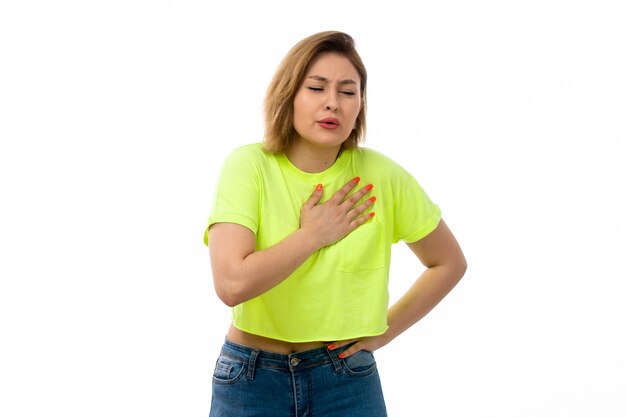 Une vue de face jeune femme séduisante en chemise verte et blue-jeans souffrant de chagrin sur le blanc