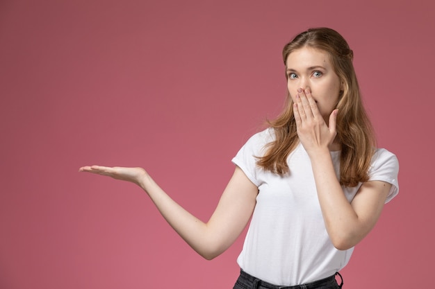 Vue de face jeune femme séduisante posant avec une expression choquée sur le mur rose modèle couleur femme jeune fille