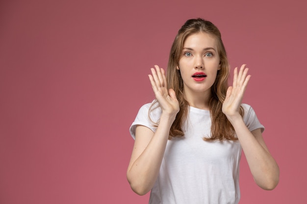 Vue de face jeune femme séduisante posant avec expression surprise sur le modèle de mur rose foncé couleur femme jeune fille