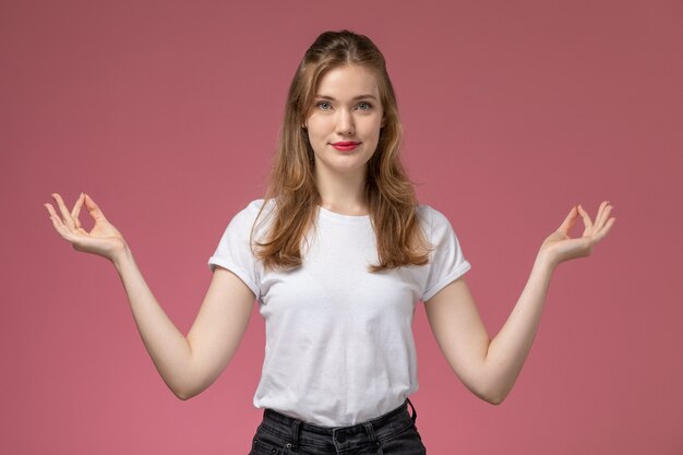 Vue de face jeune femme séduisante souriante et posant de manière méditative sur le mur rose foncé modèle couleur femme jeune fille