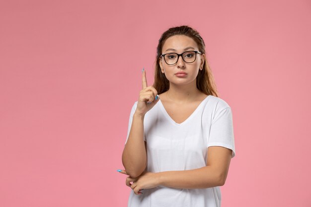 Vue de face jeune femme séduisante en t-shirt blanc posant sur le fond rose