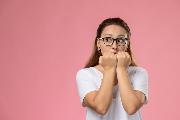 Vue de face jeune femme séduisante en t-shirt blanc posant sur le fond rose