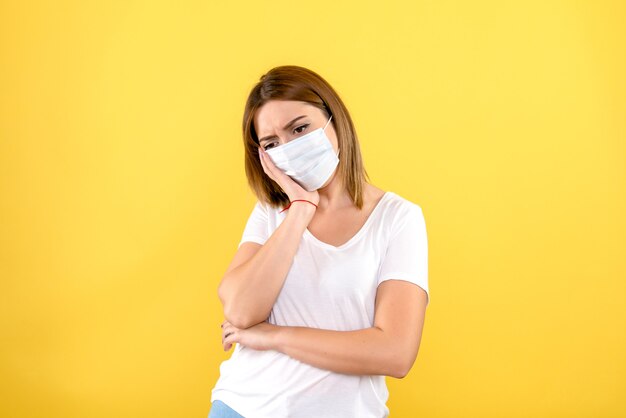 Vue de face de la jeune femme a souligné en masque sur mur jaune