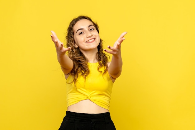 Vue de face de la jeune femme souriant joyeusement sur le mur jaune