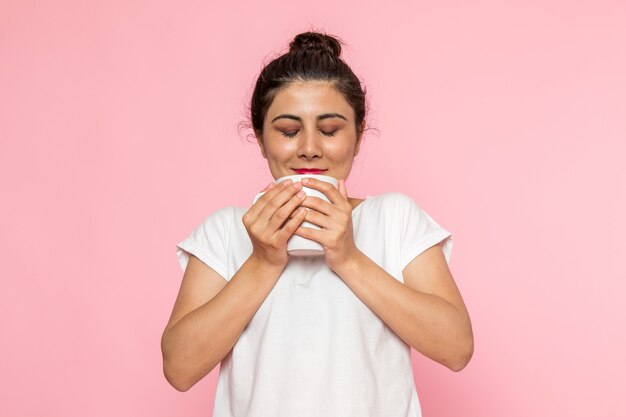 Une vue de face jeune femme en t-shirt blanc et blue-jeans, boire du café