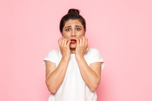 Une vue de face jeune femme en t-shirt blanc et jean bleu posant avec expression effrayée