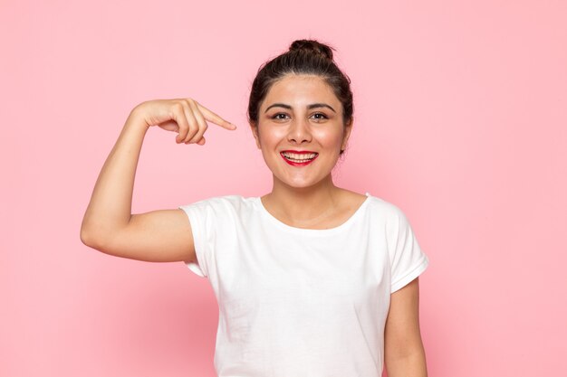 Une vue de face jeune femme en t-shirt blanc et jean bleu posant avec une expression heureuse