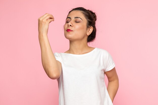 Une vue de face jeune femme en t-shirt blanc et jean bleu posant avec une expression savoureuse