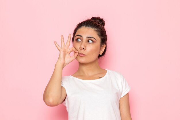 Une vue de face jeune femme en t-shirt blanc et jean bleu posant avec jolie expression