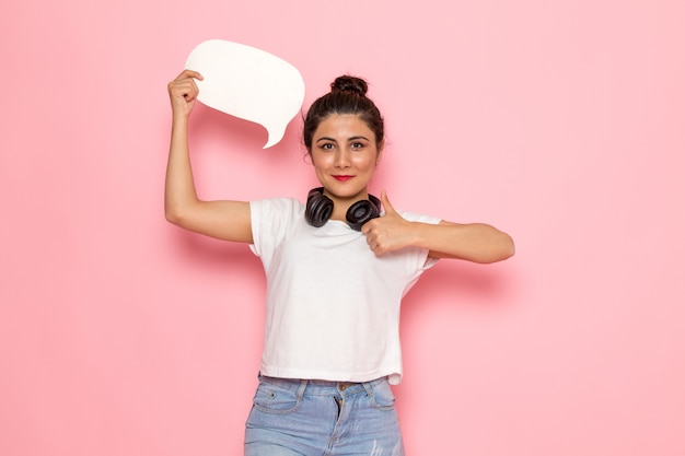 Une vue de face jeune femme en t-shirt blanc et jean bleu tenant une pancarte blanche avec sourire