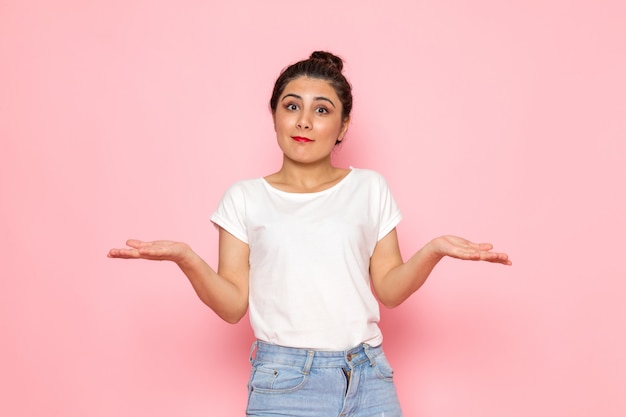 Une vue de face jeune femme en t-shirt blanc et jeans bleu posant