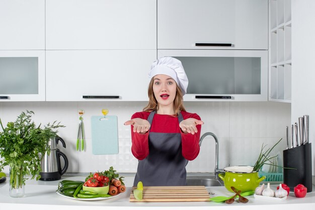 Vue de face jeune femme en tablier ouvrant ses mains