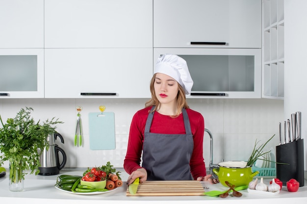 Vue de face jeune femme en tablier prenant un couteau