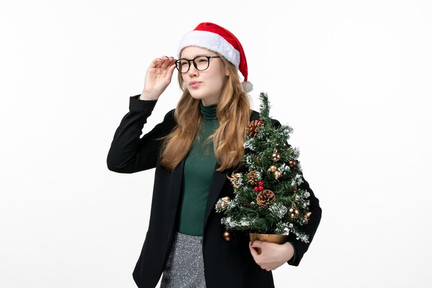 Vue de face jeune femme tenant arbre de vacances sur mur blanc jouet de Noël nouvel an