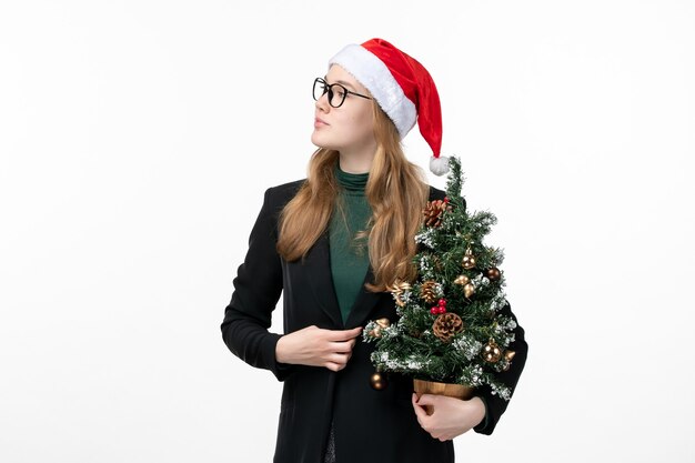 Vue de face jeune femme tenant arbre de vacances sur mur blanc jouet nouvel an Noël