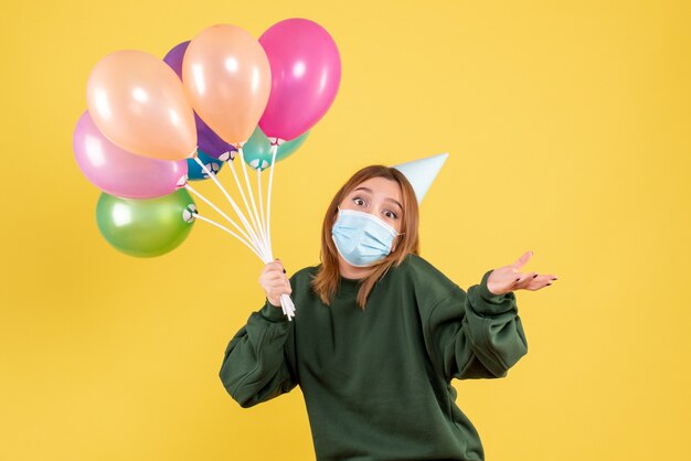 Vue de face jeune femme tenant des ballons colorés