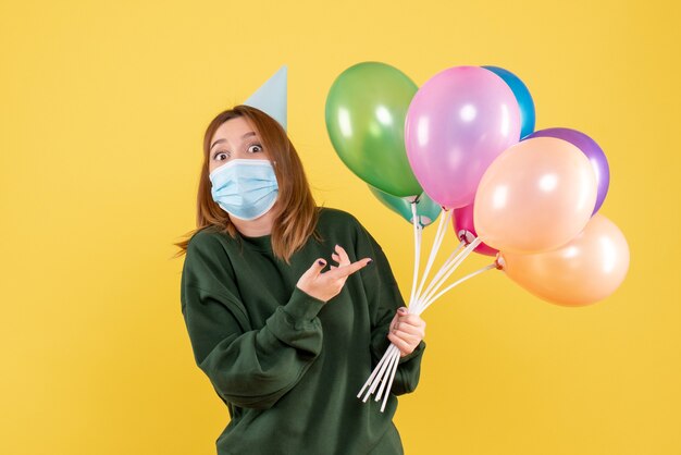 Photo gratuite vue de face jeune femme tenant des ballons colorés