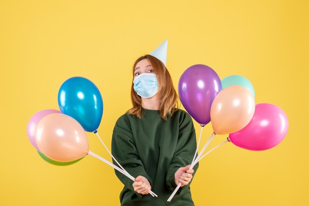 Vue de face jeune femme tenant des ballons colorés