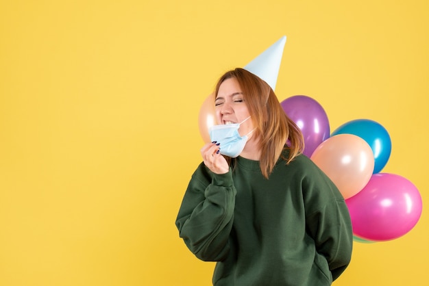 Vue de face jeune femme tenant des ballons colorés